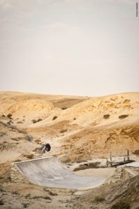 Skater Anthony Lopez en switch frontside flip sur une mini rampe à Nonidas en Namibie