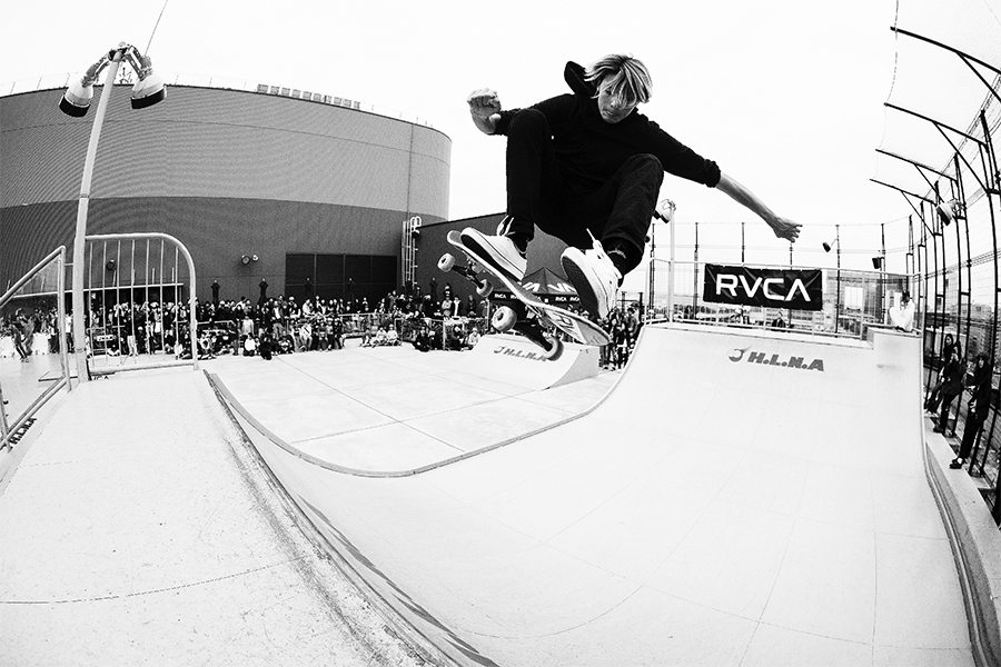 Black and white photo of Curren Caples doing a fronstside air on a mini ramp with RVCA banner on the back