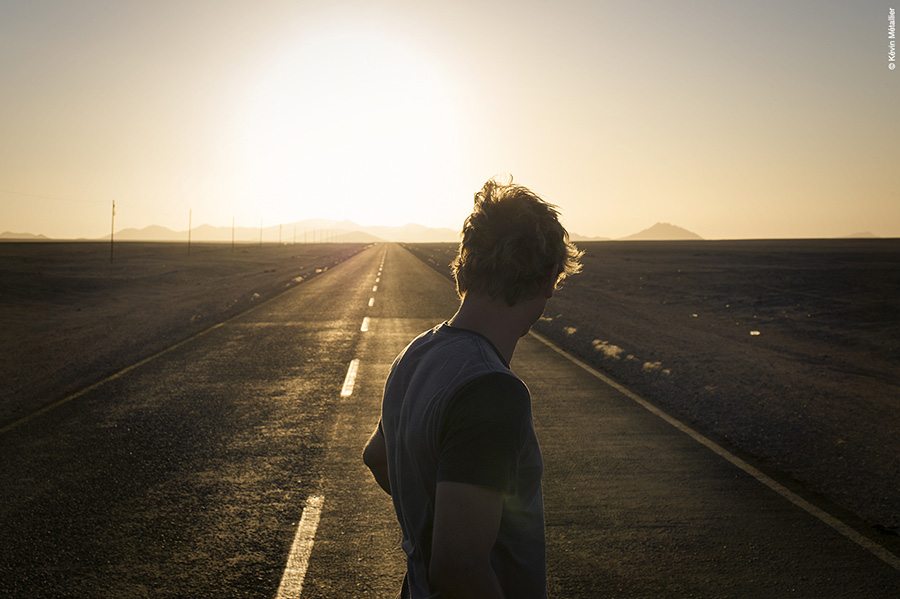 Couché de soleil en Namibie face à une route et Phillip Schuster en premier plan